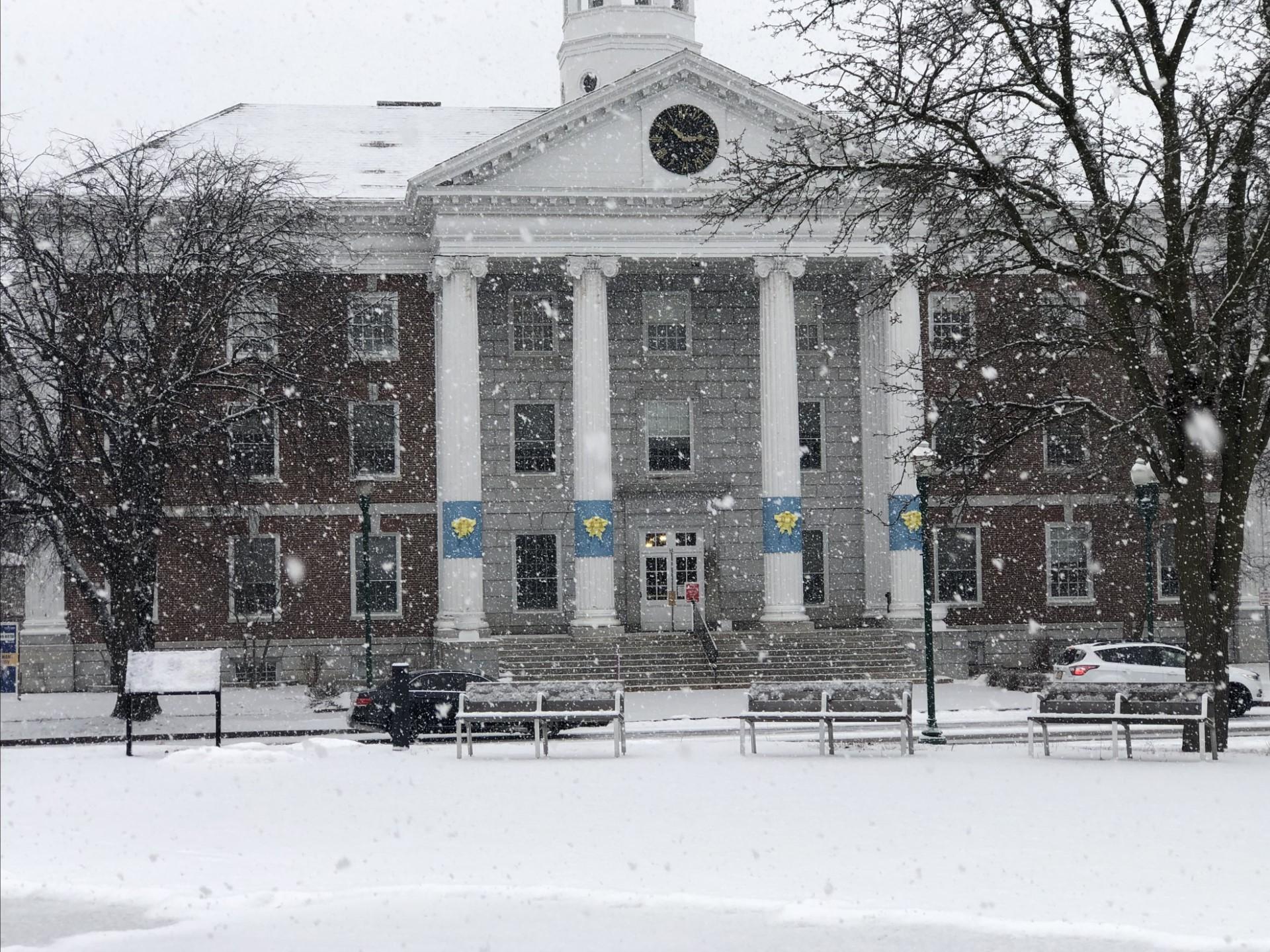 City Hall exterior of brick building with 4 white columns during a snow storm